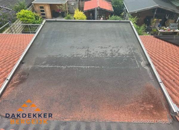 Verouderd plat dak met slijtage tussen schuine daken in Bergeijk Verouderd plat dak met slijtage tussen schuine daken in Bergeijk