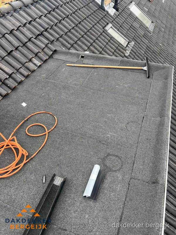 Plat dak reparatie met gereedschap en loodstroken in Bergeijk