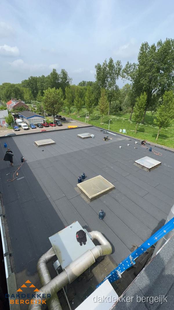 Dakdekker aan het werk op groot plat dak met bitumen in Bergeijk