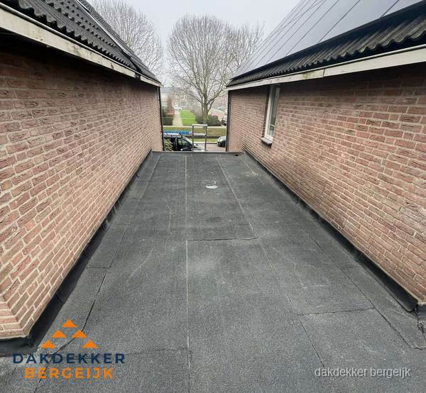 Plat dak met bitumen dakbedekking tussen bakstenen muren in Bergeijk Plat dak met bitumen dakbedekking tussen bakstenen muren in Bergeijk