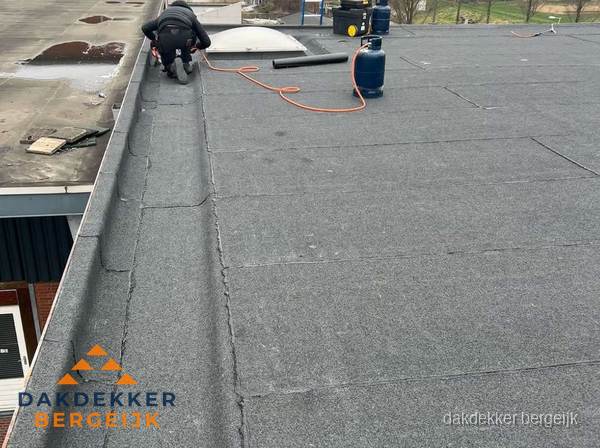 Dakdekker repareert bitumen dakbedekking op groot plat dak in Bergeijk Dakdekker repareert bitumen dakbedekking op groot plat dak in Bergeijk